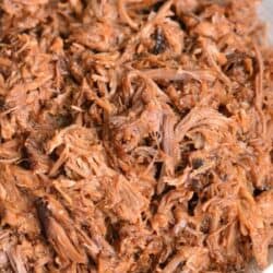 Pulled pork with bbq sauce mixed in inside a white bowl.