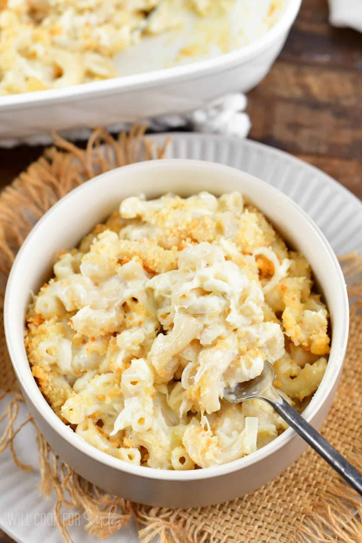 crab mac and cheese in a bowl with a fork full of mac and cheese on a piece of burlap.