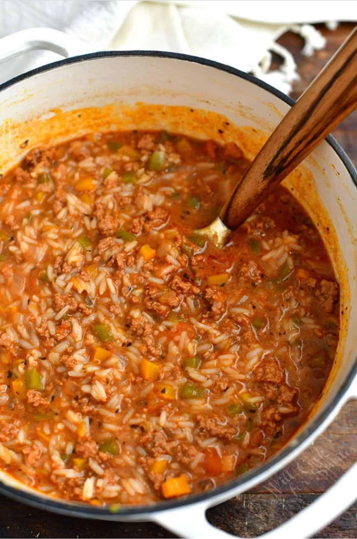stuffed pepper soup in a dutch oven with a big serving spoon.