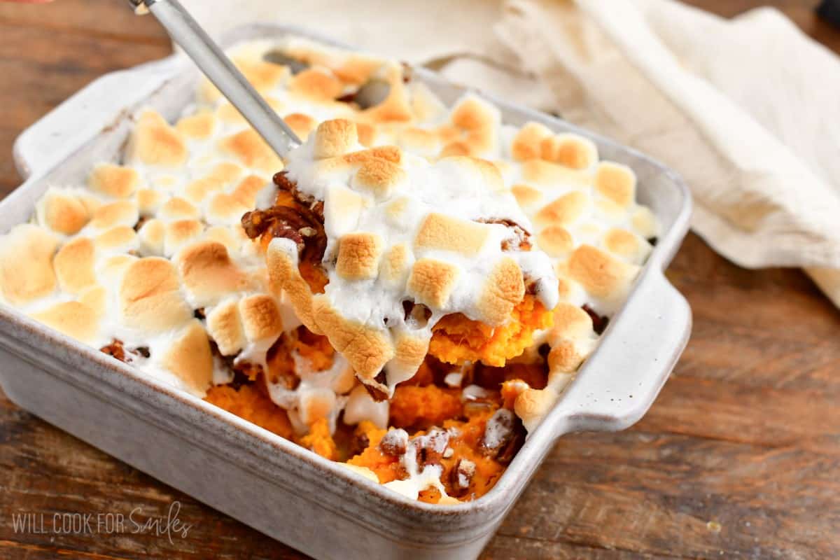 scooping out some sweet potato casserole with marshmallow topping.