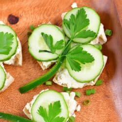 Shamrock sandwiches on a wood plater with green onions as a garnish around them.