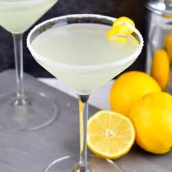 Lemon drop martini in a martini glass with sugar on the rim and a lemon twist on the side of the glass as garnish.
