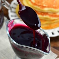 blueberry syrup pouring off spoon into the saucer cup.