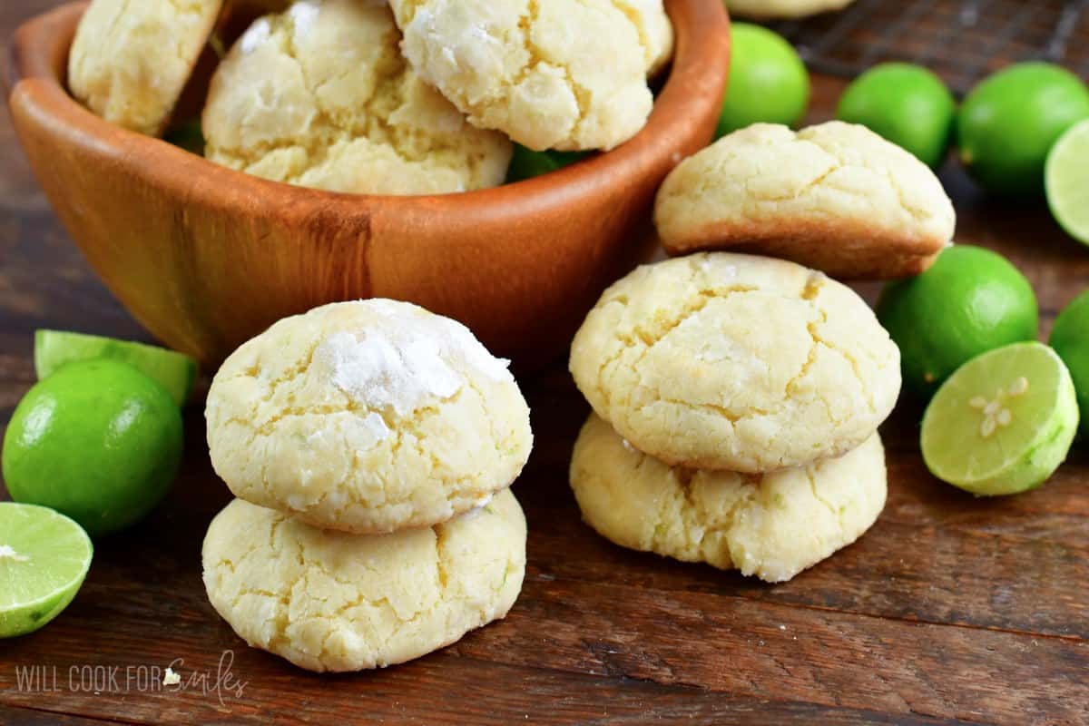 Coconut cream cheese cookies on a wood surface with some cookies stacked in a bowl.