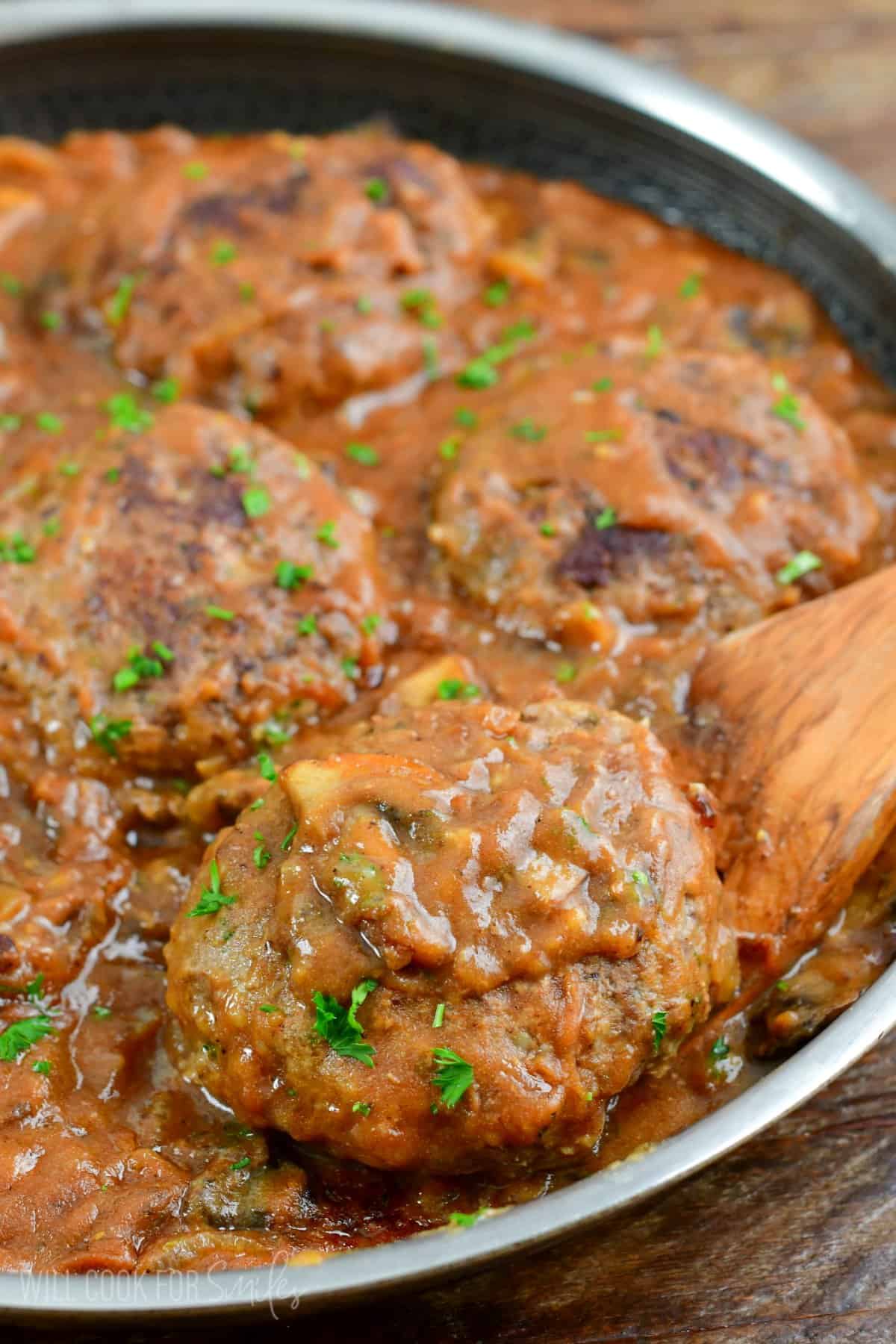 taking one of the Salisbury streaks out of the pan with a wooden spatula.