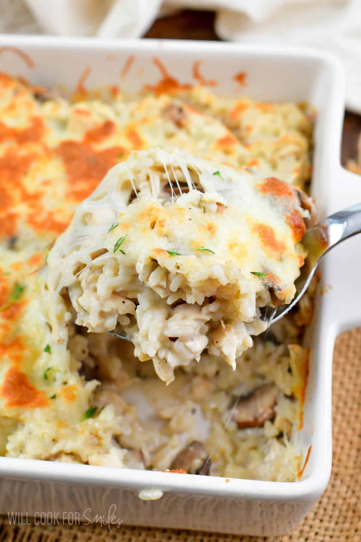 Scooping some of the chicken mushroom rice casserole out of the baking dish.