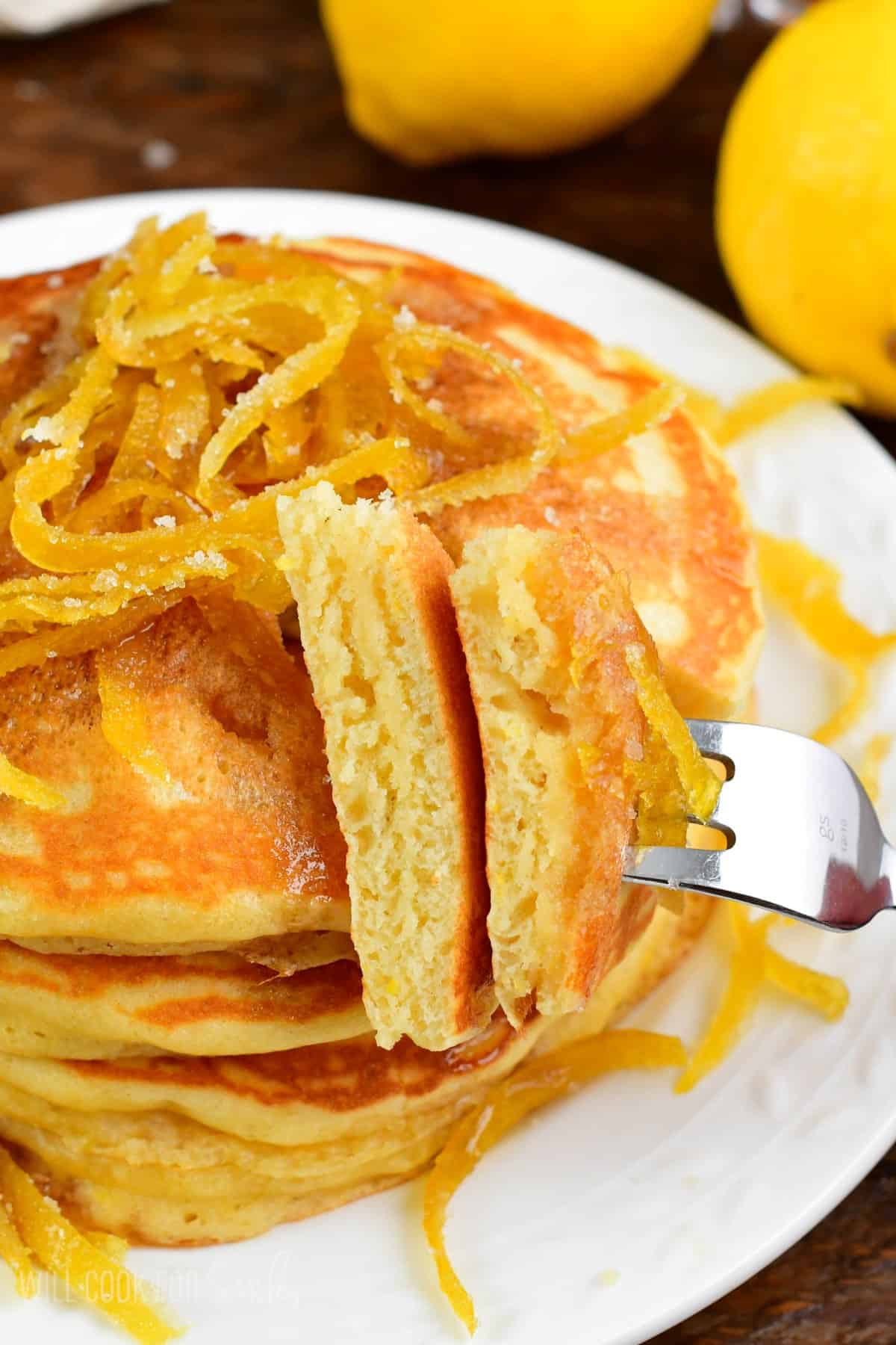 Lemon pancakes lemon peels on top with a cut slice on a fork.