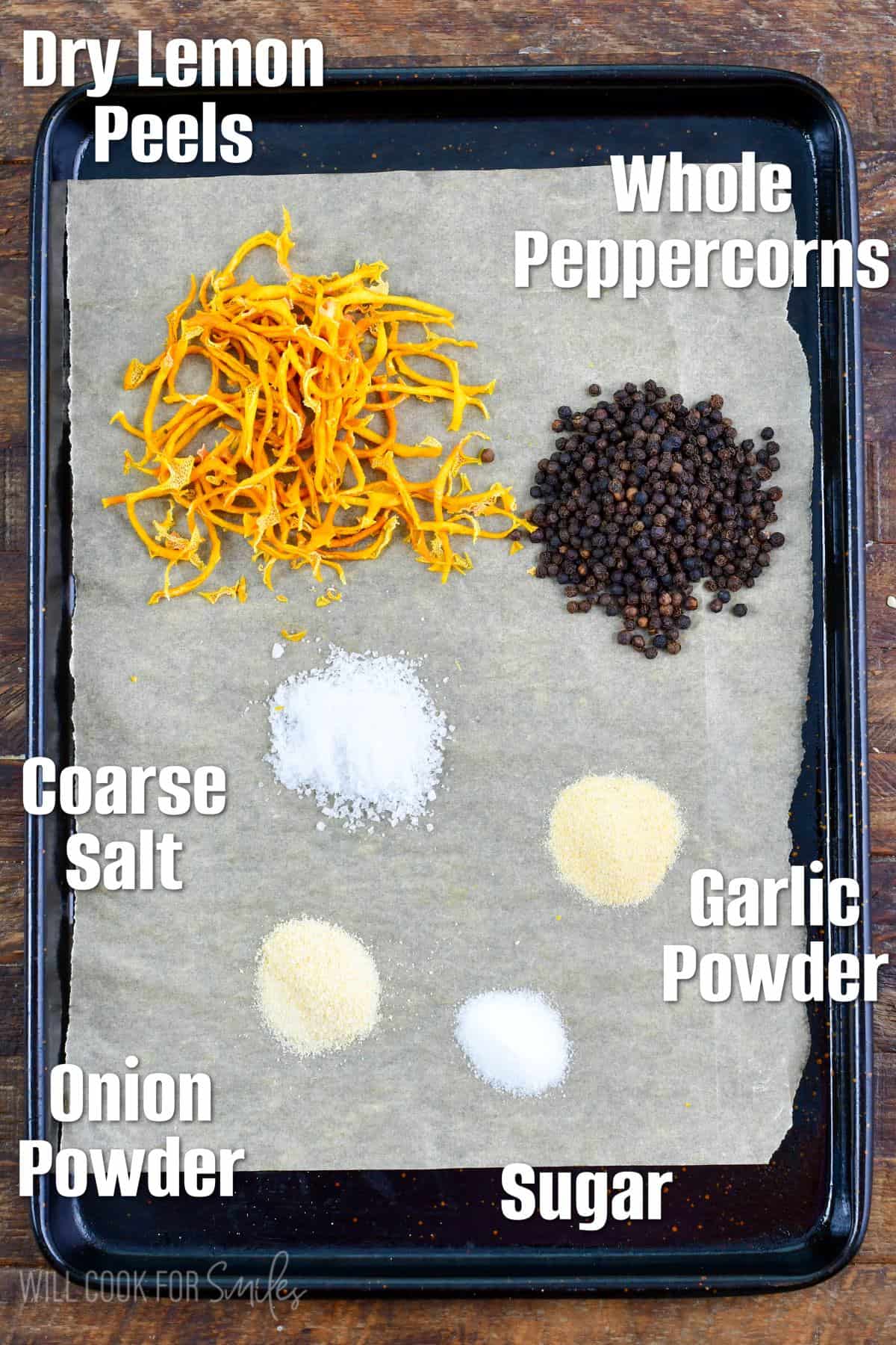 ingredients to make lemon pepper seasoning spread out on the baking sheet and labeled.