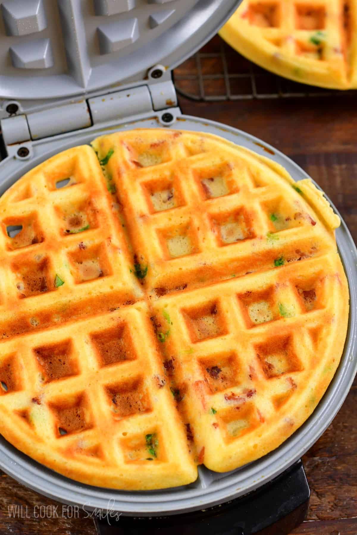 Cooked savory waffles cooked and in a waffle maker with the lid open.