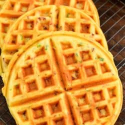 four cooked savory waffles on a wire rack on a wood surface.