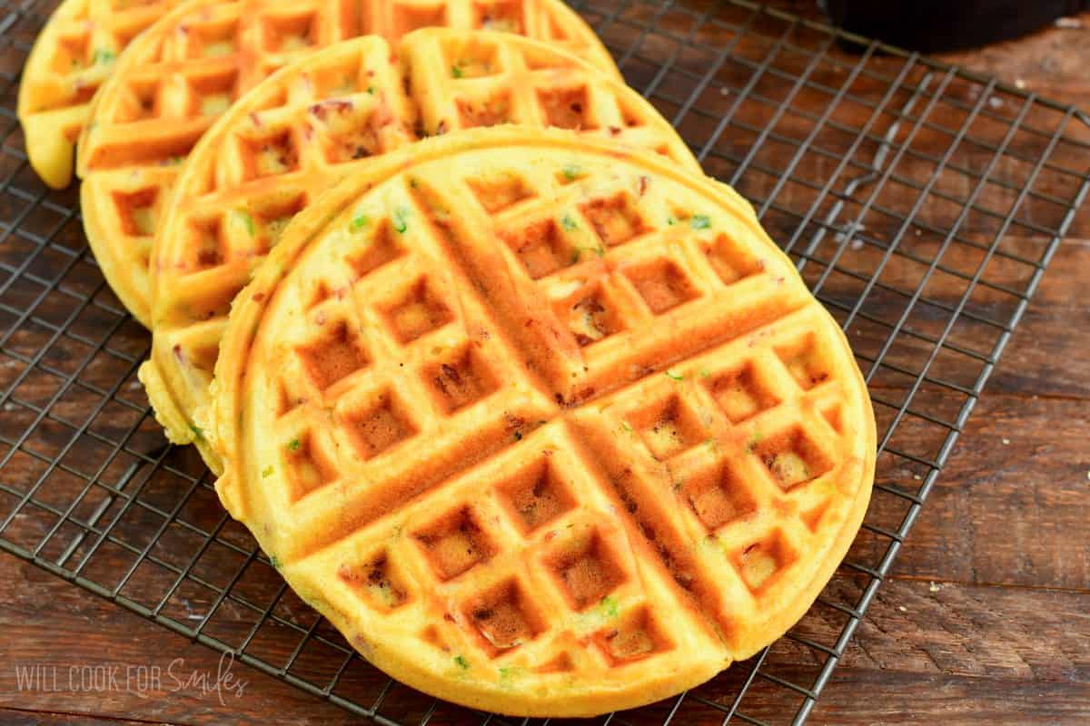 four cooked savory waffles on a wire cooking rack.