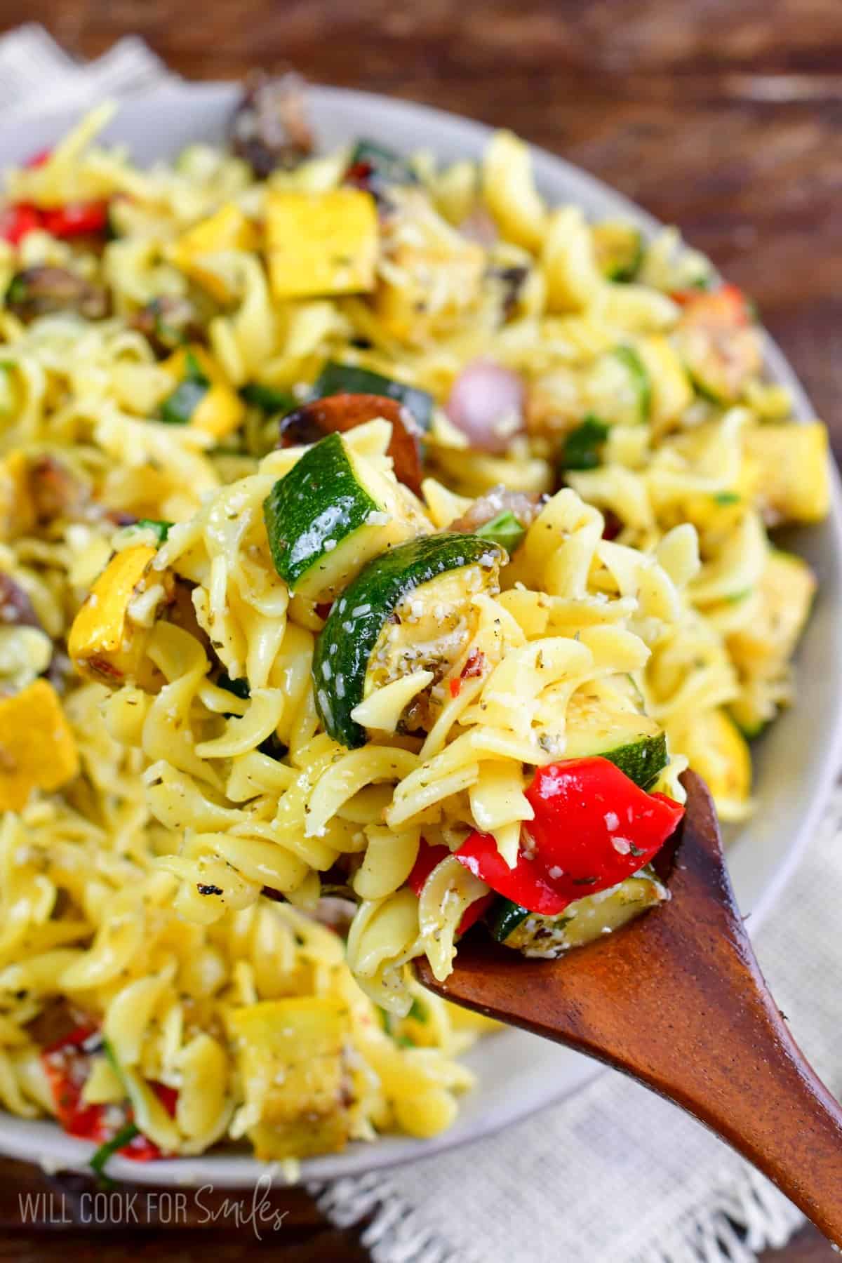 Scooping up some grilled pasta salad with a wooden spoon.