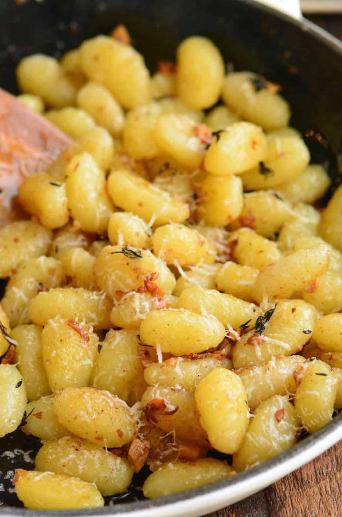 sauteed gnocchi in the skillet with garlic butter thyme and grated parmesan cheese.