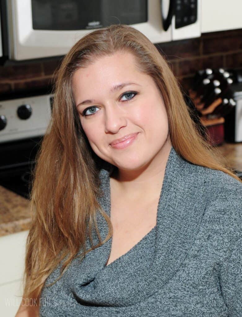 Lyuba Brooke wearing a grey sweater in the kitchen smiling at the camera.