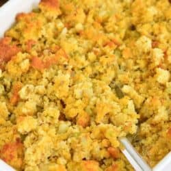 fluffing cornbread dressing with a serving spoon.