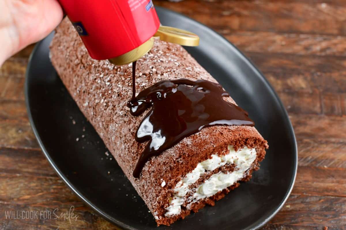 adding chocolate drizzle on top of the chocolate cake rolls.
