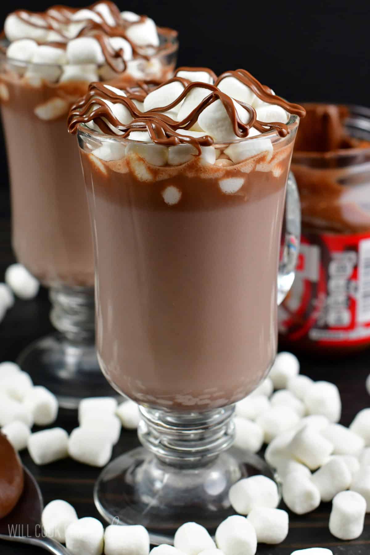 A side view of nutella in a glass with marshmallows and nutella on the top.