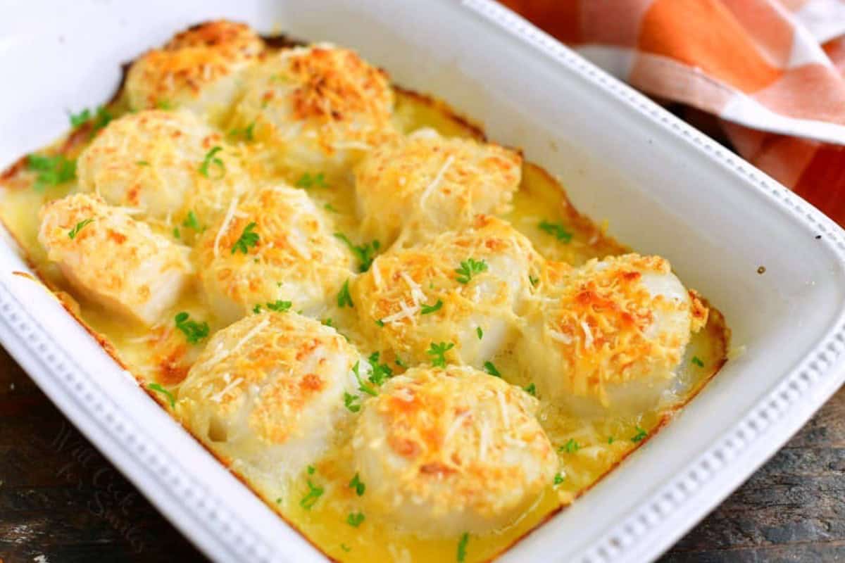 baked scallops in the white baking with with crunchy parmesan cheese on top.