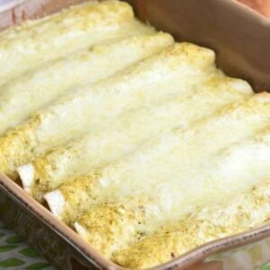 several enchiladas baked in verdes sauce and cheese on top.