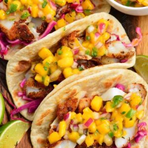 Three blackened fish tacos with mango salsa on top.
