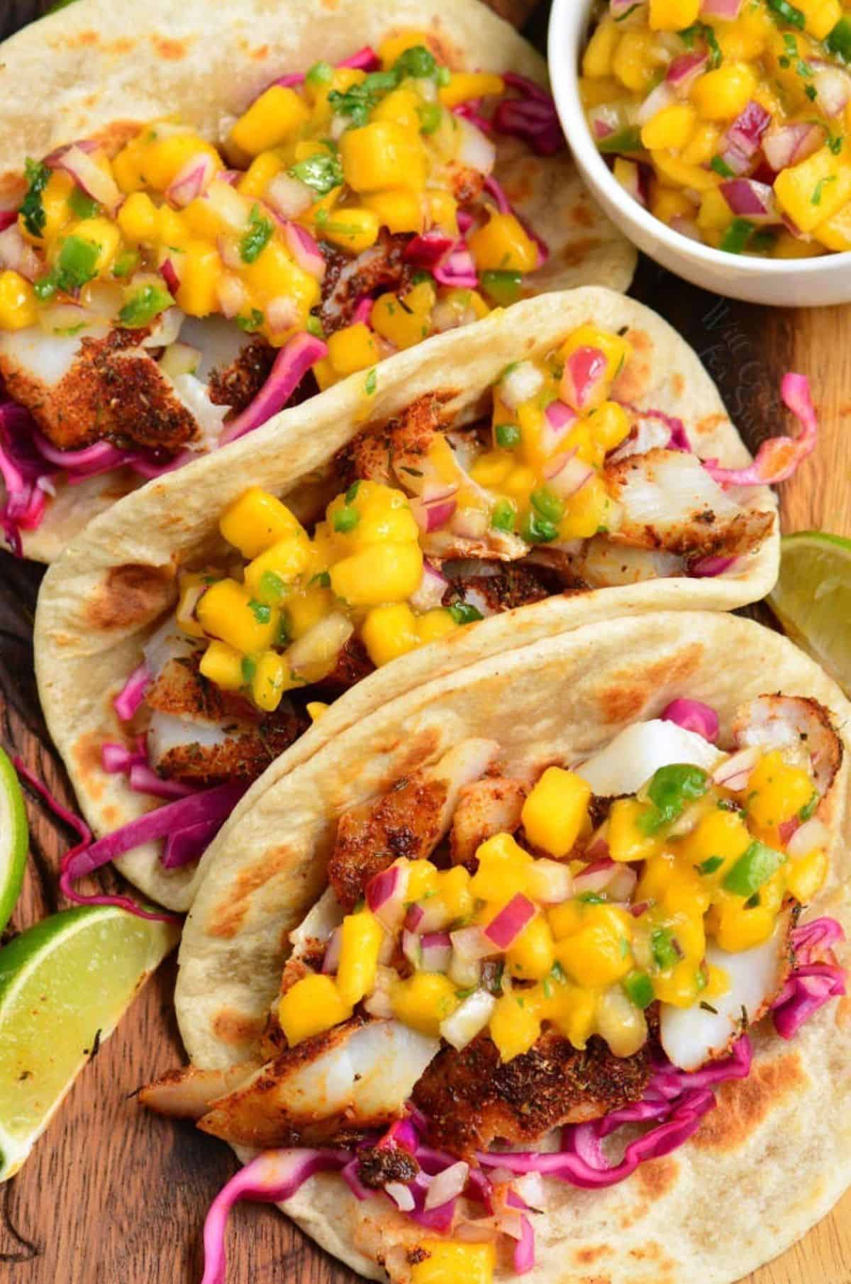 Three blackened fish tacos with mango salsa on top.