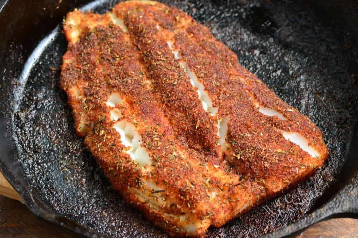 Blackened talapia icooked n a cast iron skillet.