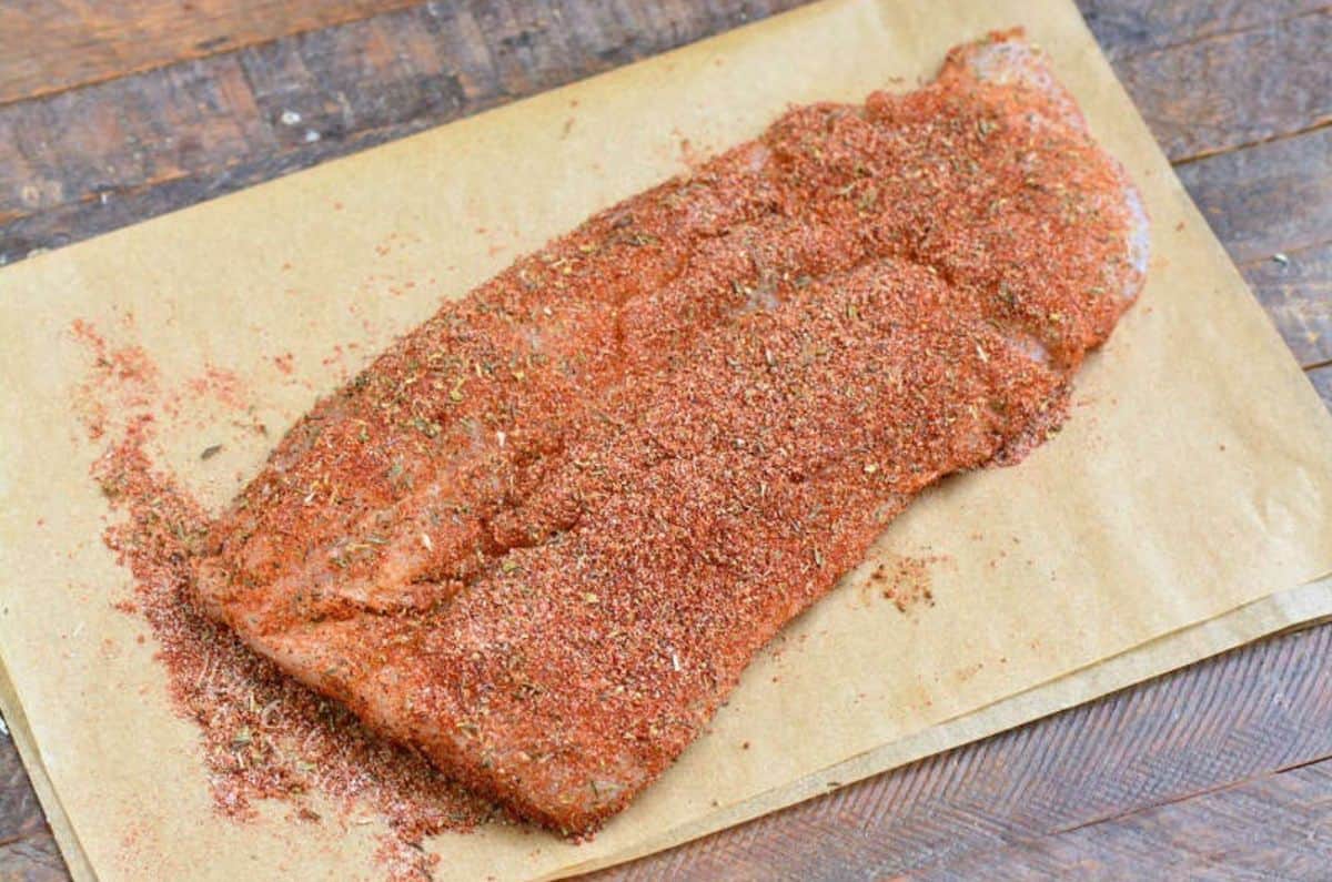 blackened seasoning on a fish filet on a sheet of parchment paper.