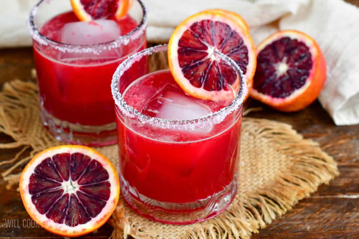 Two blood orange margaritas in a salt rimmed glass with a slice of blood orange as garnish.