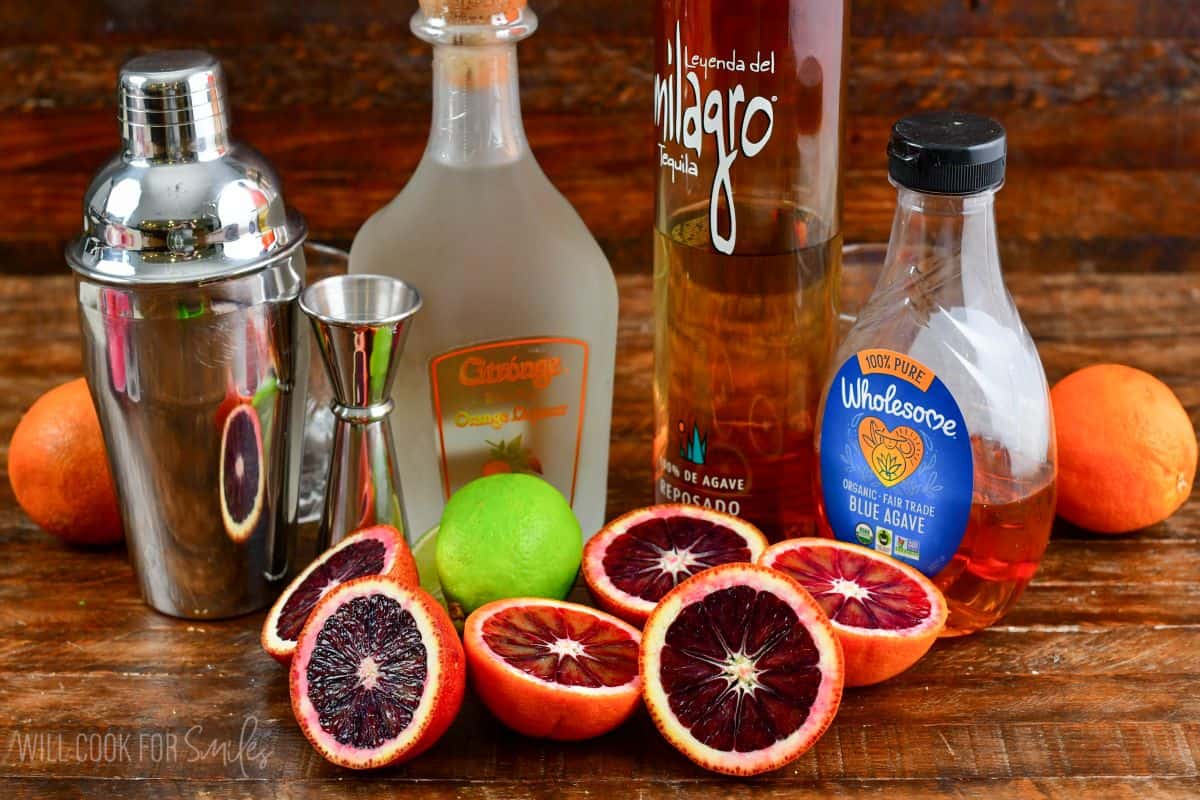 Ingredients for blood orange margaritas on a wood surface.