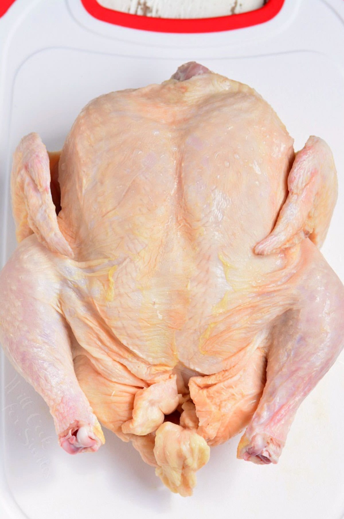 whole chicken on a plastic cutting board.