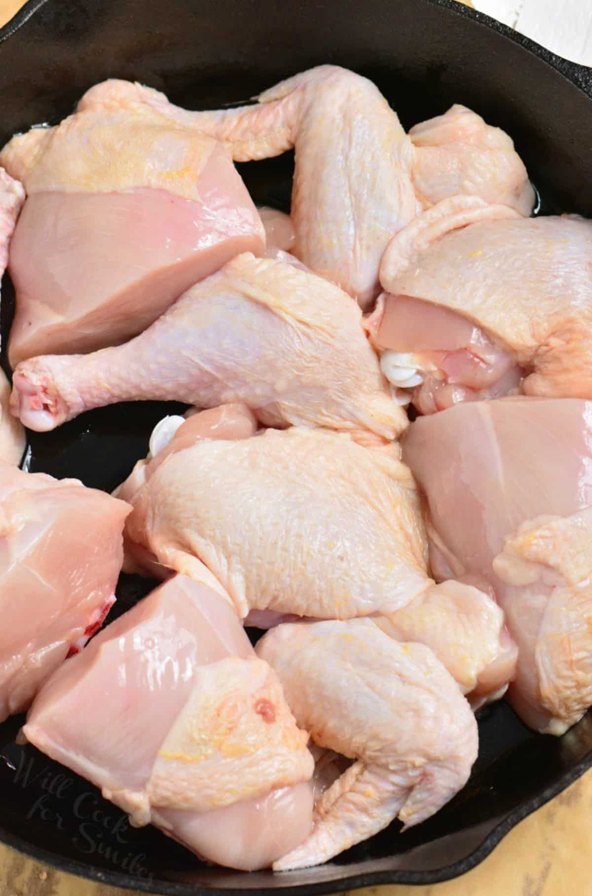 Whole chicken broke down into peices in a cast iron skillet.