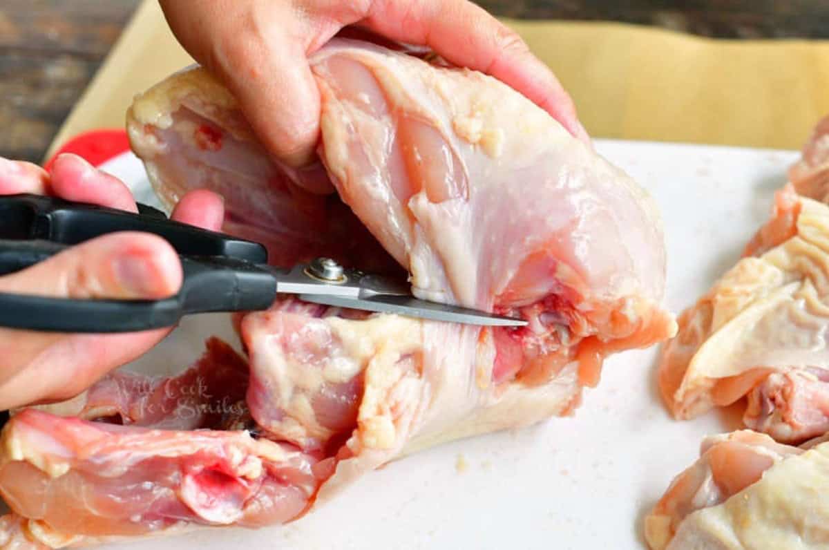 Using sissors to break down the chicken breast.