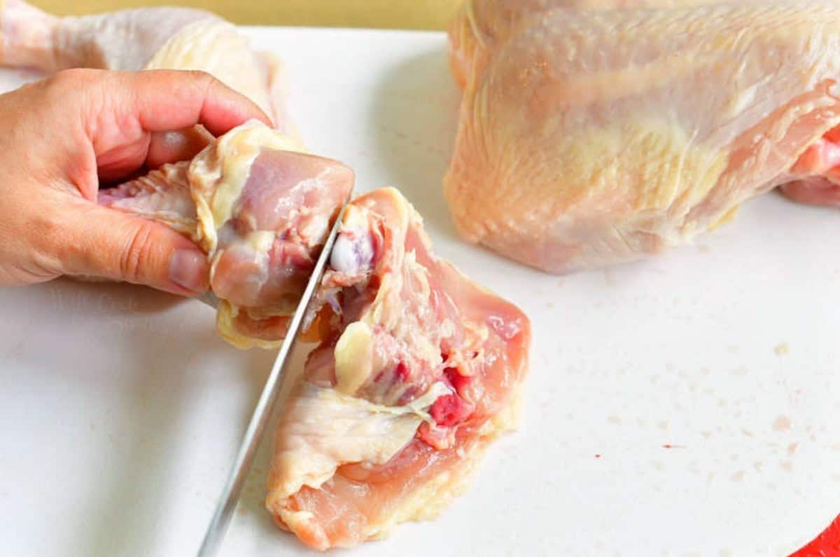 Using a knife to separate the leg from the chicken.