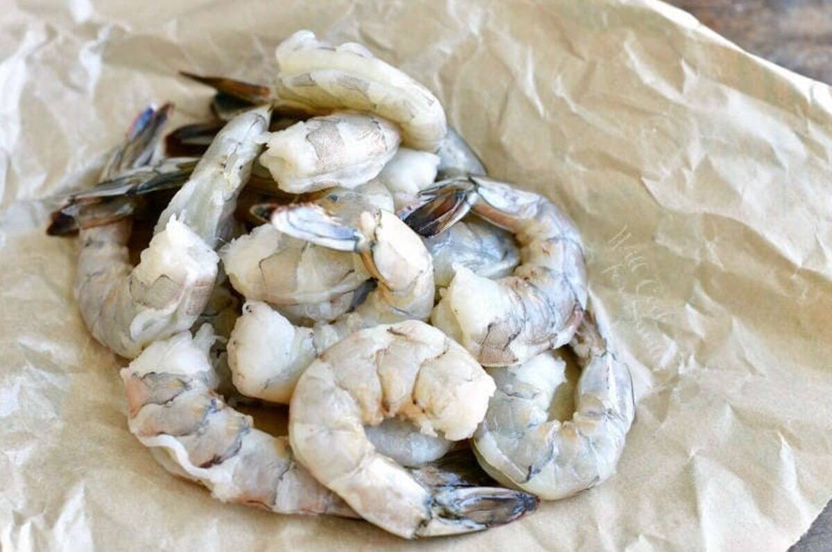 Pile of shrimp that cleaned and deveined on parchement paper.