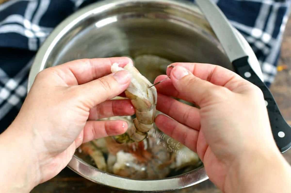 Pulling the vein out of the shrimp to devein it.