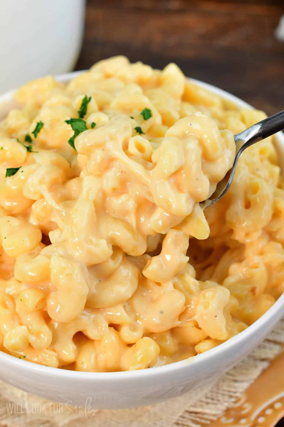 scooping some cheesy mac and cheese from a bowl using a fork.