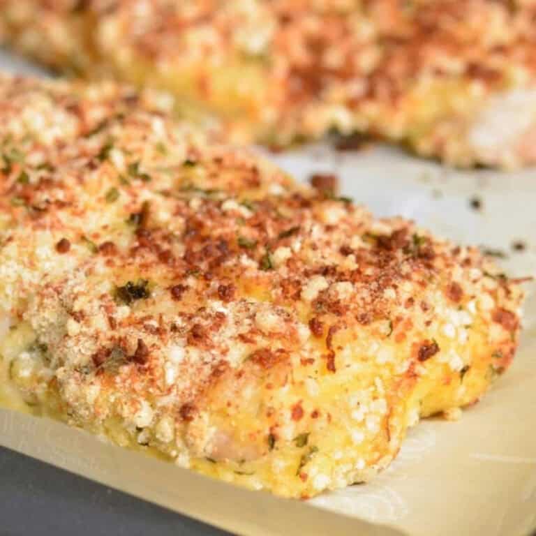 crispy parmesan crusted piece of mahi mahi on parchment paper covered baking sheet.