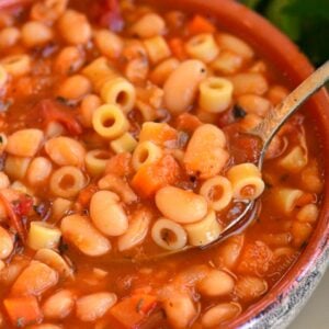 spooning out some pasta e fagioli soup from the bowl.