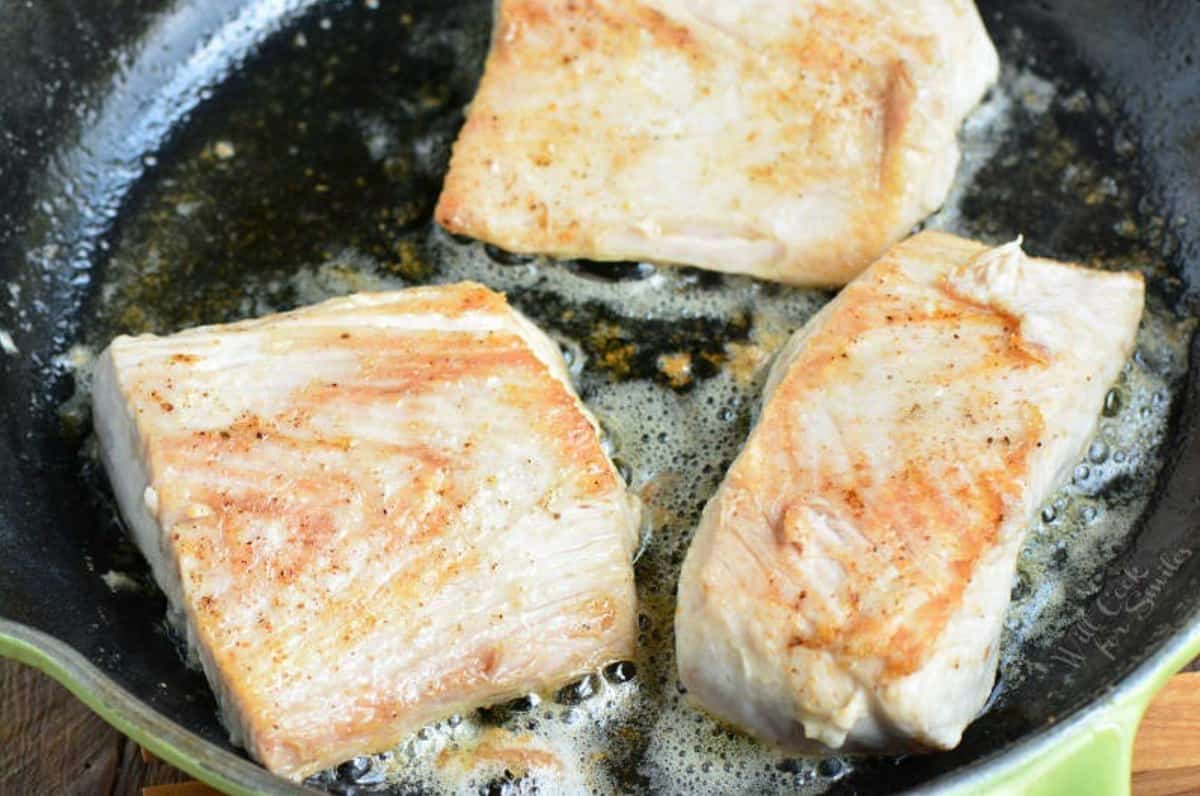 searing three mahi mahi filets on the skillet in butter and seasoning.