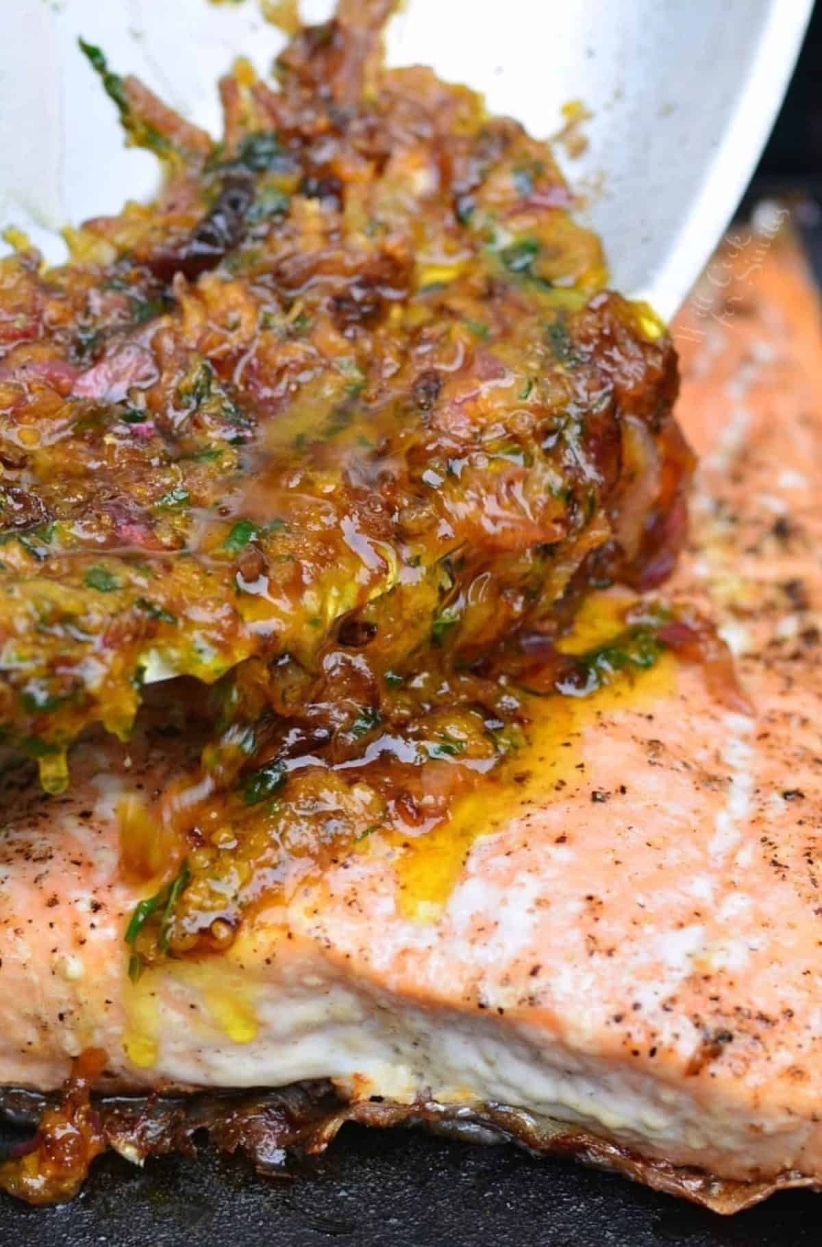 pouring brown butter citrus sauce over the grilled salmon.