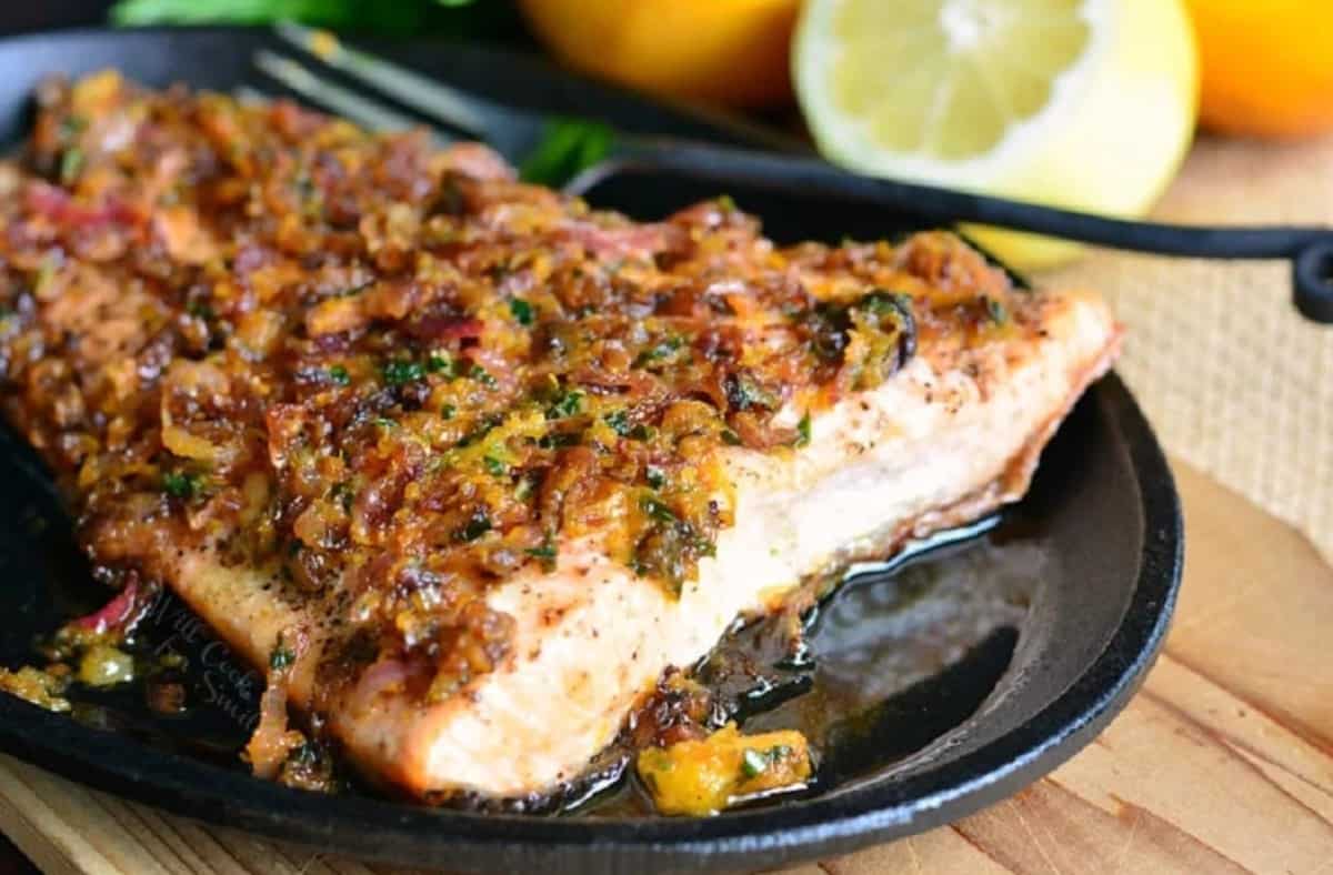 grilled salmon topped with brown butter citrus sauce in a skillet.
