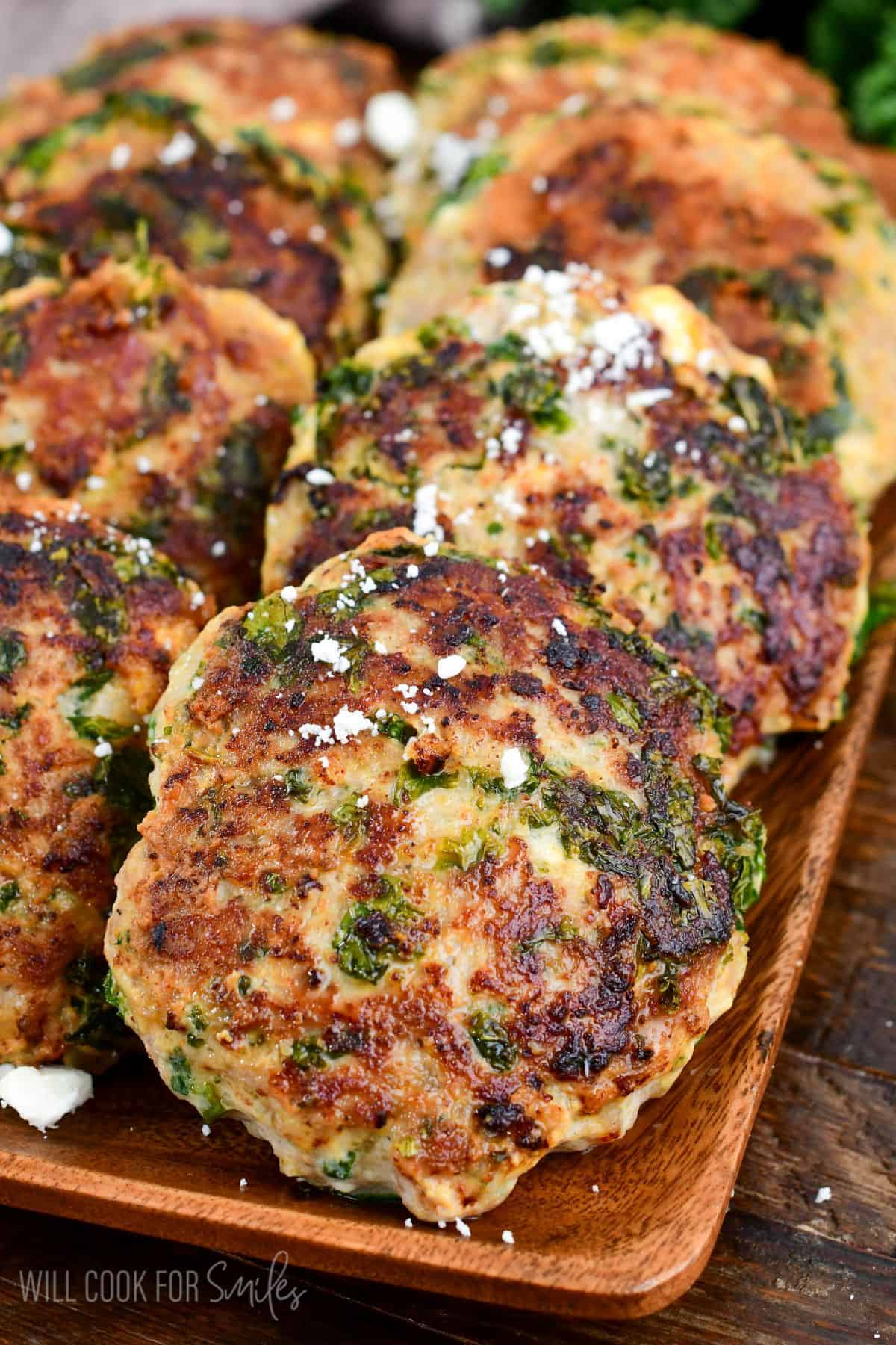 cooked turkey burgers laid out on the platter topped with a little feta cheese.