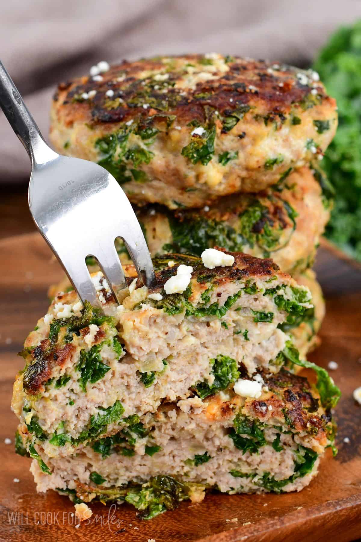 cut turkey burger with kale and feta stacked on the top of another half.