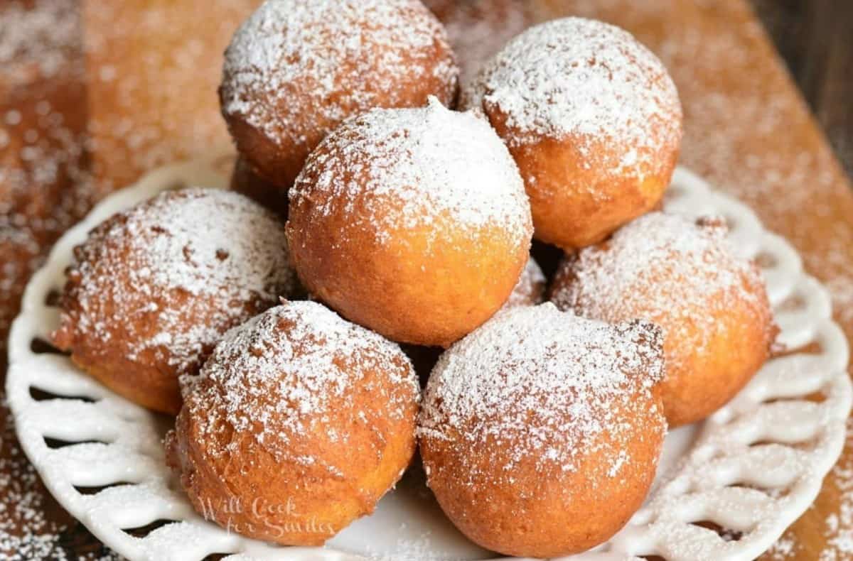 several stacked donut holes on a plate with powdered sugar.