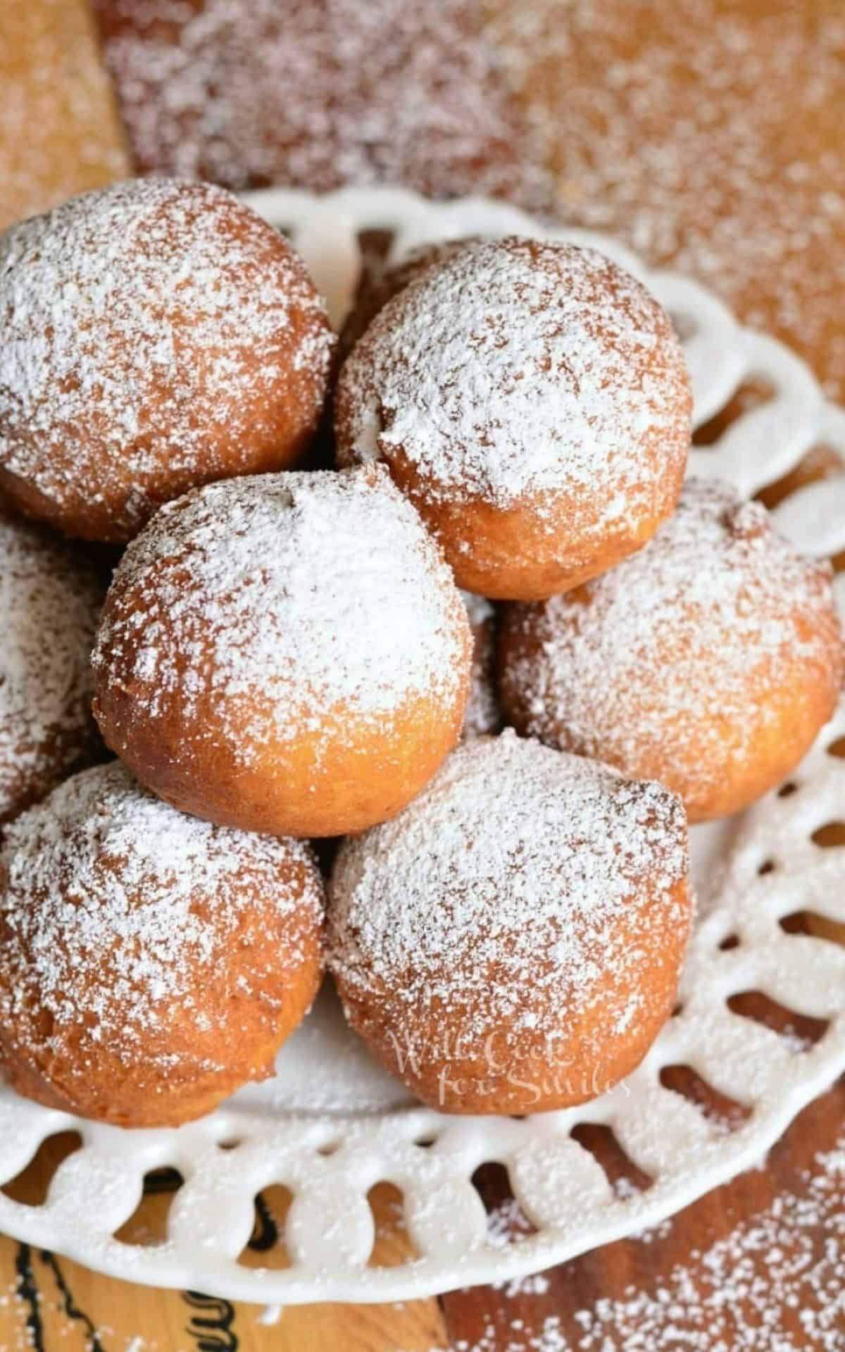 stacked ricotta donuts on a plate with powdered sugar.
