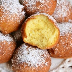 a plate of stacked donut holes with one bite taken out.