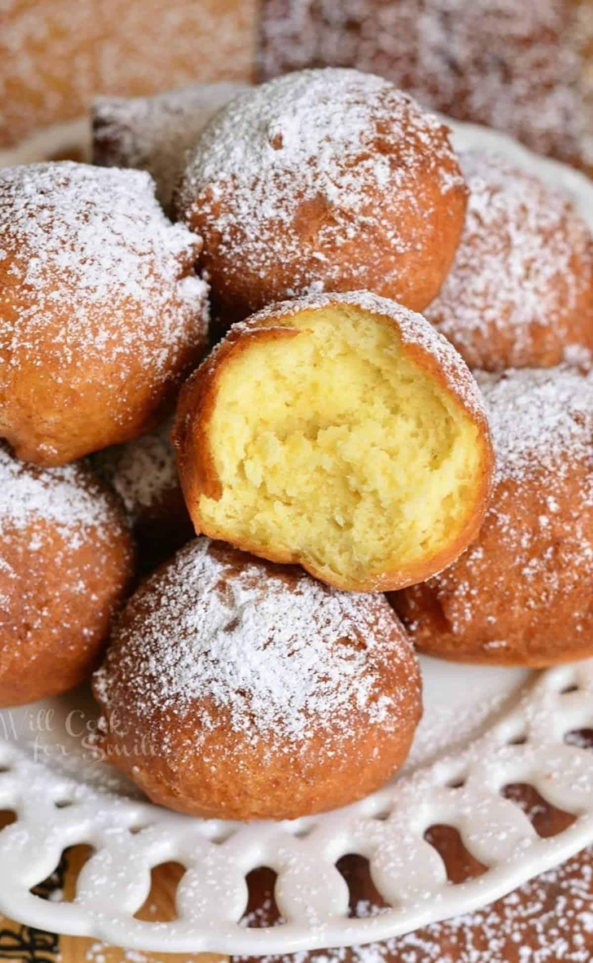 a plate of stacked donut holes with one bite taken out.