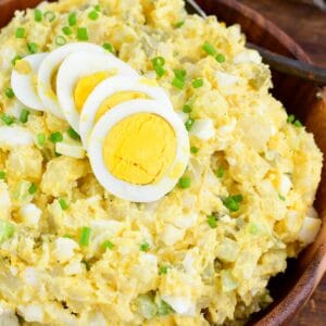 potato salad with eggs, pickles, and creamy mustard sauce in a bowl topped with egg.