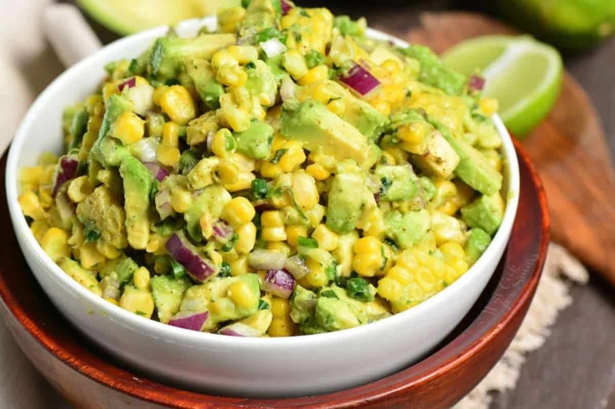 Avocado Corn Salsa in a bowl on top of a wood bowl.