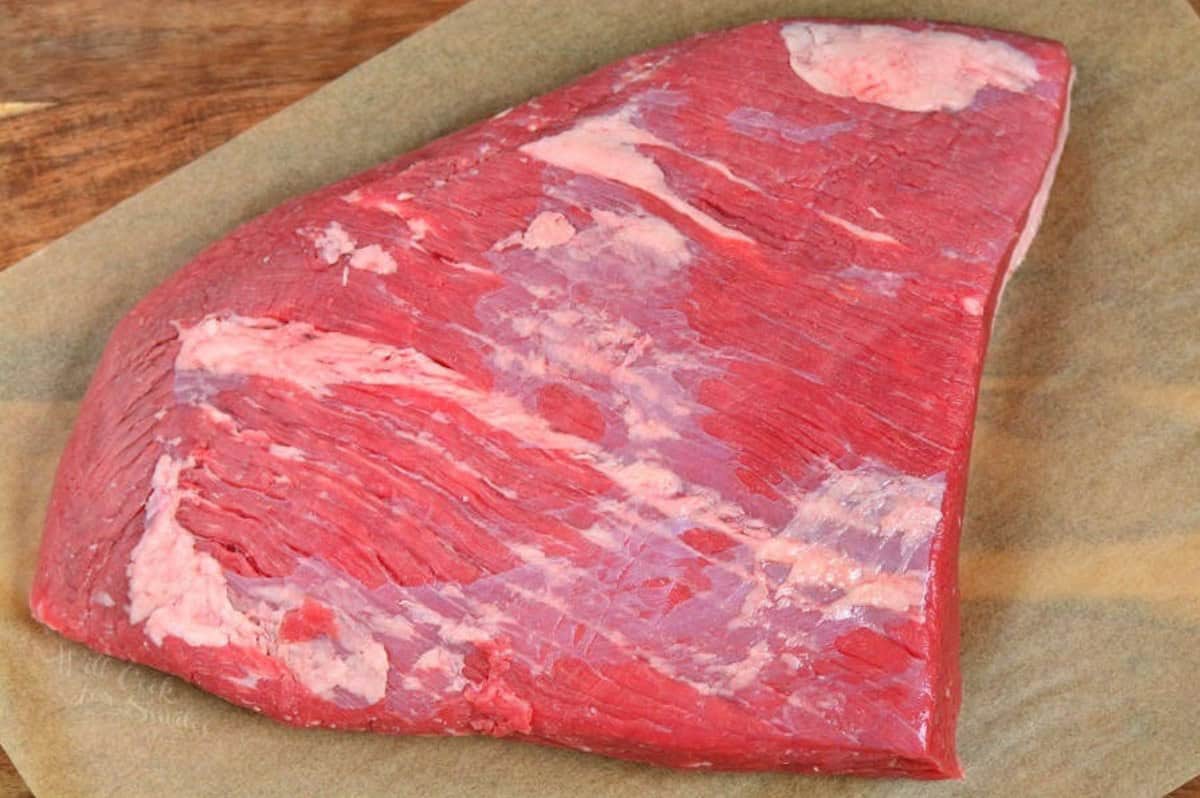 uncooked flat cut of a beef brisket laying on the parchment paper.